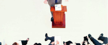 A man presenting on a lecturn to his team