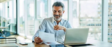 a man looking at a piece of paper in front of a computer