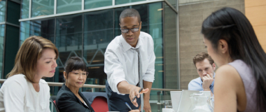 A team working in the office with the boss leading the discussion