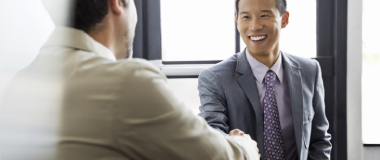 Two co workers shaking hands and smiling