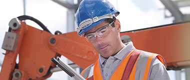 A construction worker with a big crane behind him