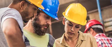 Three construction workers looking at blueprints on site