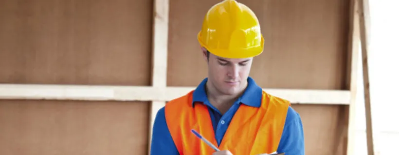 A construction worker writing notes on a pad