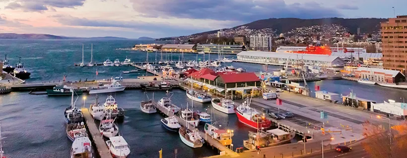 A city in Hobart near a wharf with boats docked