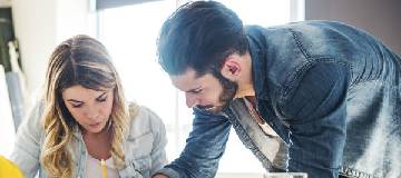 Two employees working together in the meeting room of their office