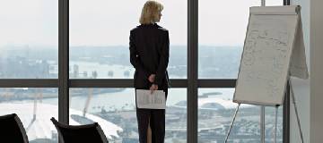 A woman in her office looking out a big window to the city