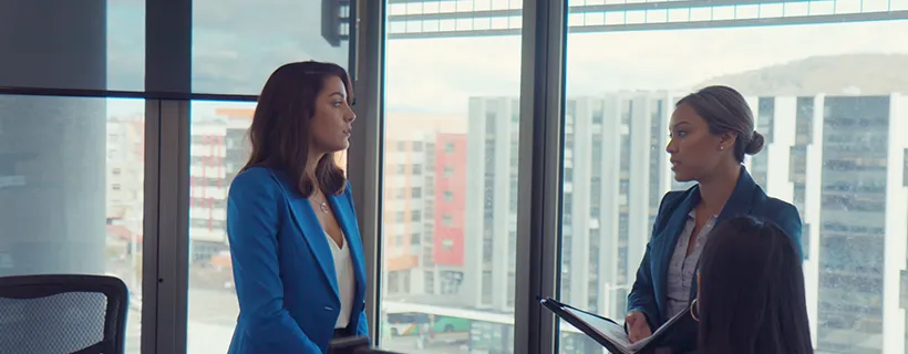 Two co workers having a meeting in front of a window looking out to the city