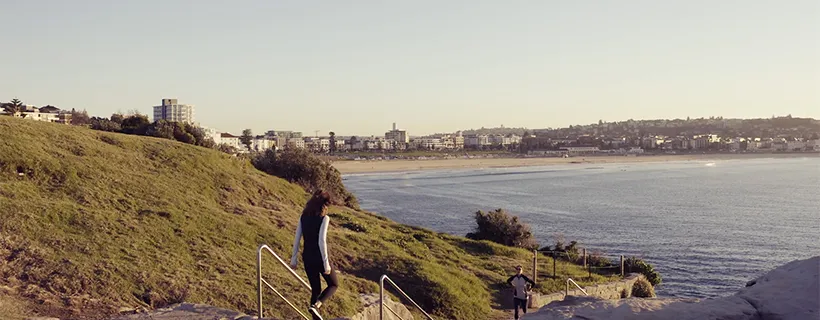 People walking down steps towards a beach on a nice day
