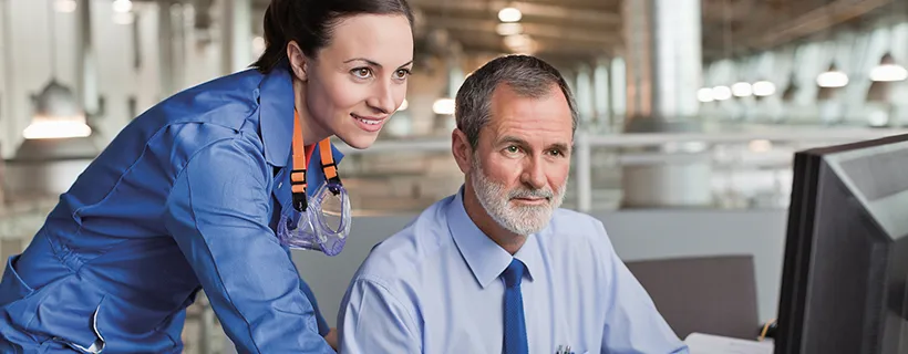 a manufacturing operations supervisor helping her colleague on the computer