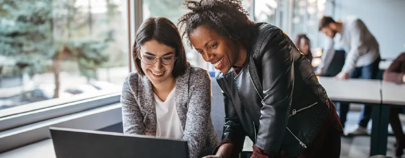 two young female professionals looking at the computer screen in an office setting 