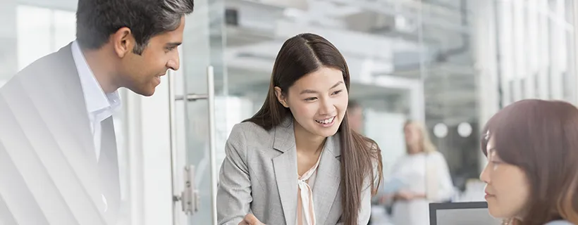 Three employees smiling while working in a team meeting