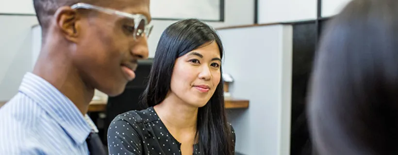 Three employees in the office smiling