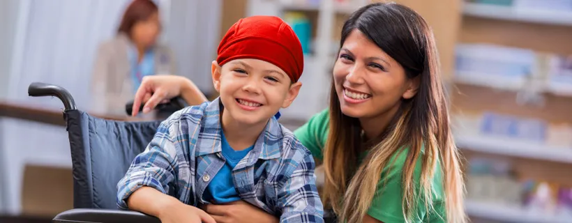 a woman and young child in the wheelchair smiling together