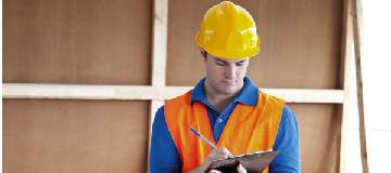 A construction worker holding a pad and writing notes