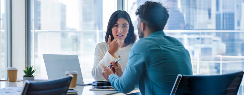 two coworkers talking in a meeting room