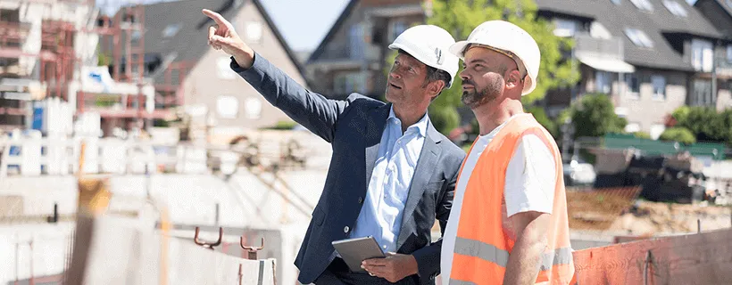 a contractor talking with construction site worker pointing at the site