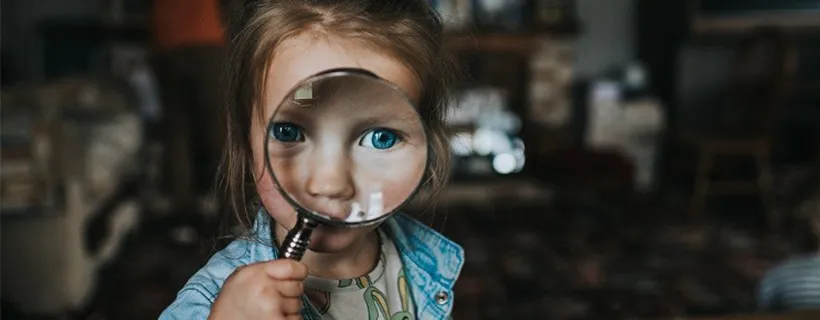 A young girl holding a magnifying glass