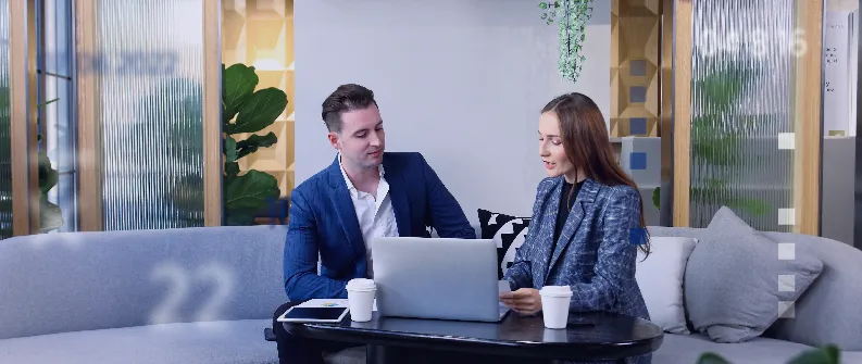 two employees sitting in front of a laptop discussing salaries