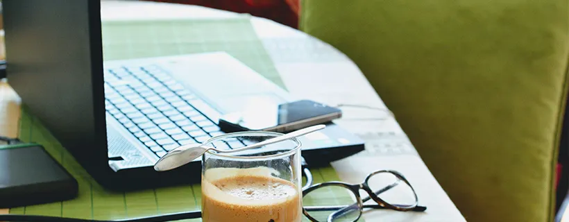 A desk with a coffee and a laptop on it