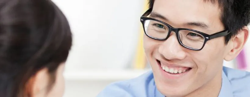 A man smiling intently while having a discussion with a co worker