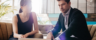 Two employees in a room looking at a laptop