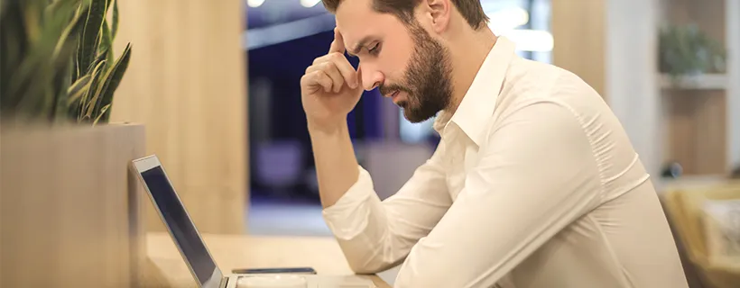 A man looking stressed working on his laptop