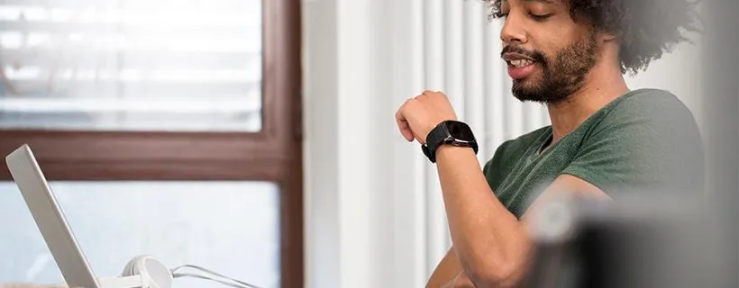 A man working at his desk from home checking his watch