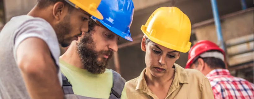 Three construction workers looking at blueprints on site