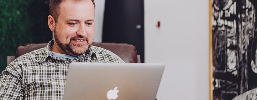 A man sitting on a couch using his laptop