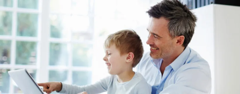 A father with his son on his lap having fun on their computer maintaining work-life balance