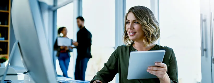 a Recuitment Manager holding a piece paper and looking at her computer