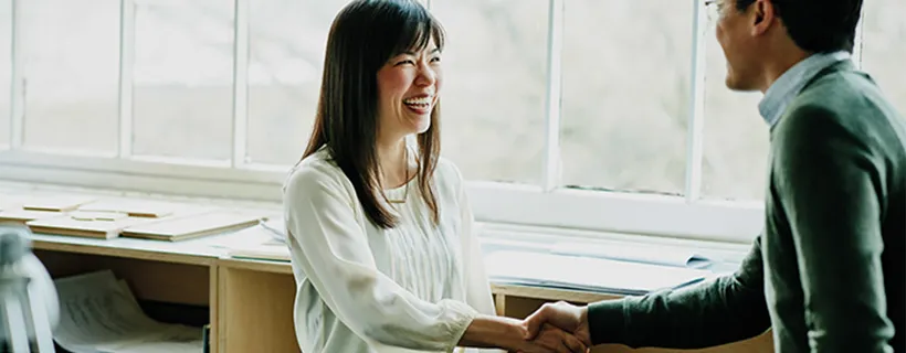 Two employees shaking hands and smiling