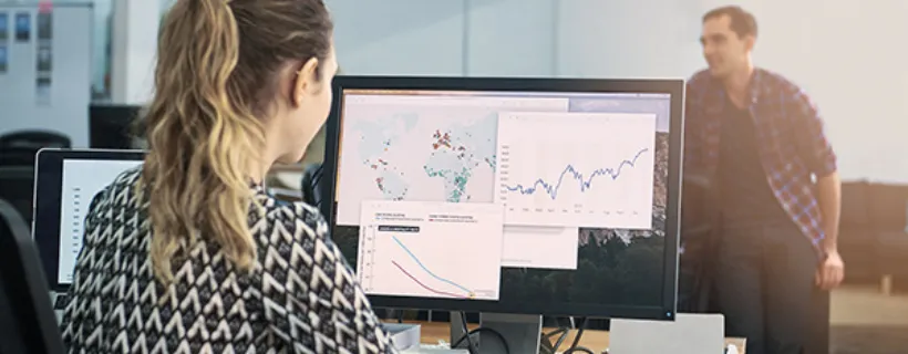 An employee working in the office on her computer with charts displayed on the screen